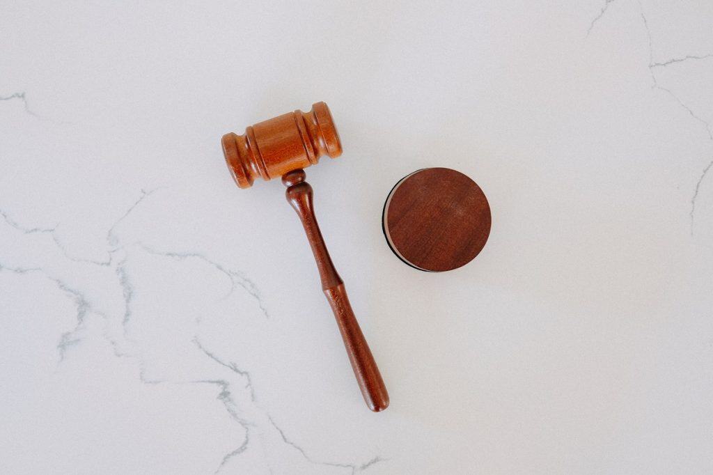 A wooden gavel and sound block are placed on a white marble surface.