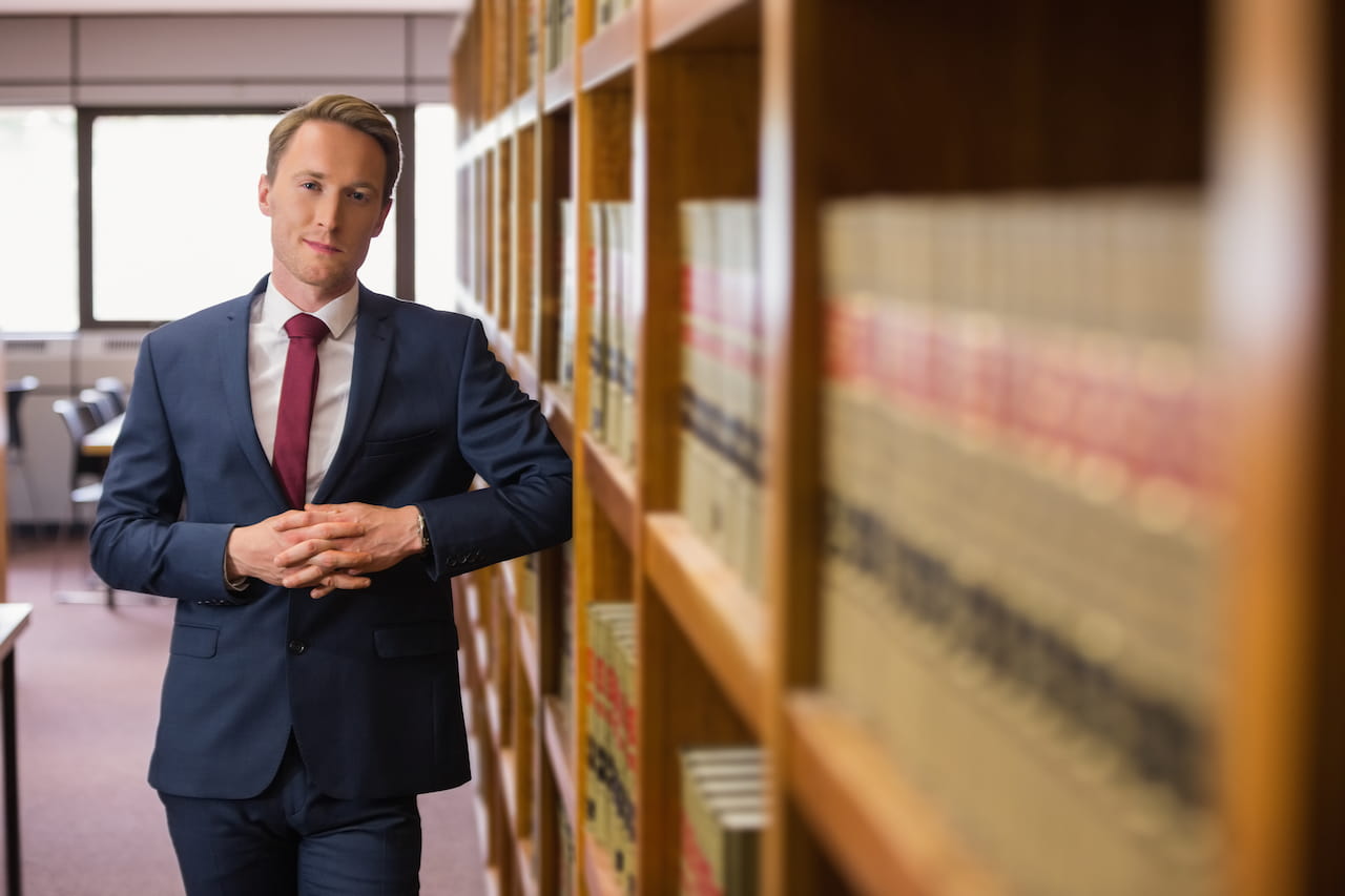 A Lawyer Leaning Against A Row of Bookshelves