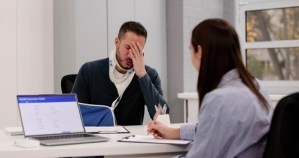 Injured man wearing neck brace and arm sling at health insurance claim desk