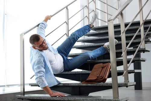 man falling down building stairs with briefcase beside him