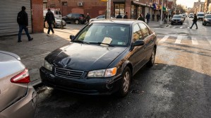 Toyota Camry sedan with parking ticket on windshield at urban street corner