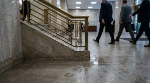suited professionals walking through marble courthouse hallway with brass staircase railing