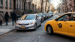 New York taxi and Honda sedan navigating congested urban street near brownstones
