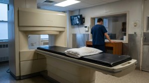 medical technician standing beside MRI machine with patient table and pillow